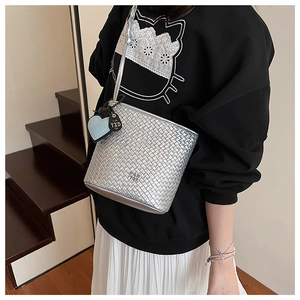 Vue détaillée d'un sac seau tissé argenté avec un pendentif en cœur bleu et texture métal