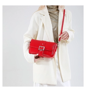 Détail du sac à bandoulière en cuir ciré rouge avec boucle argentée porté par un mannequin