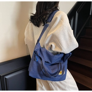 Detail of dark blue denim tote bag with wide strap and cute cartoon bear patch