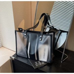 Détail du sac cabas noir translucide avec rayures verticales et poignées en cuir