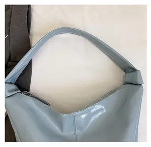 Détail du sac à bandoulière en similicuir brillant bleu clair avec sangle large et zip