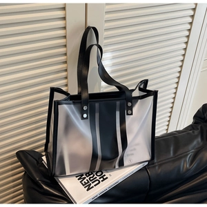 Detail of transparent tote bag featuring black vertical stripes and metal rivet reinforcement