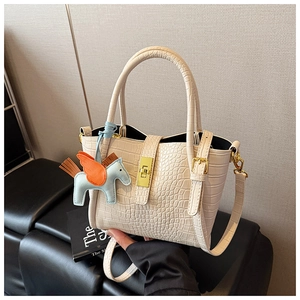 Dettaglio borsa a secchiello beige coccodrillo con ciondolo cavallo blu e fibbia d'oro