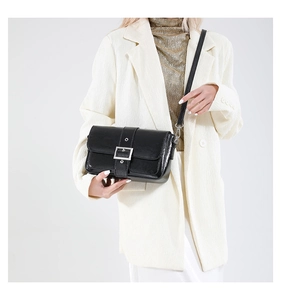 Détail du sac bandoulière noir avec boucle argentée et bandoulière en cuir texturé