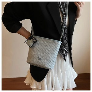Détail du tissage croisé d'un sac seau bleu clair avec une bandoulière en cuir souple