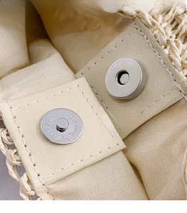 Detailed macro view of the metal magnetic clasp and neat fabric lining on the woven bag