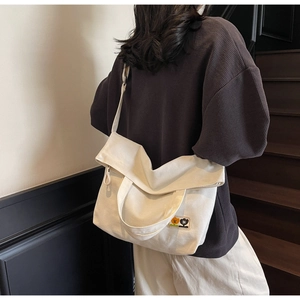 Model wearing a white canvas crossbody bag with vintage floral patches on indoor stairs
