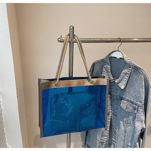 Detail of transparent blue PVC tote bag with champagne trim and thick rope handles