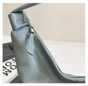 Détail de la fermeture éclair en métal et texture cuir brillant sur un sac seau chic