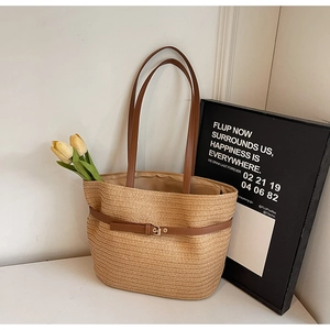Vue détaillée du sac cabas en paille tissée avec bandoulière et boucle en cuir brun
