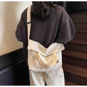 Detailed back view of a large vintage off-white canvas tote bag worn by a model