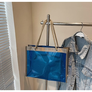 Detail of transparent blue tote bag with beige woven rope handles and metal eyelets