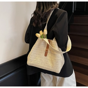Close-up of handmade woven straw tote bag with brown leather clasp and fine textures