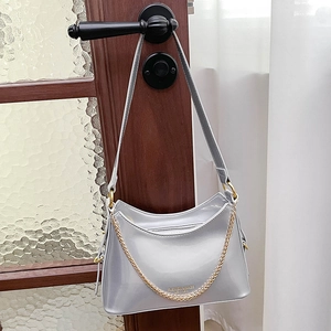 Close-up of silver mirror hobo bag with gold chain detail and stamped fashion logo