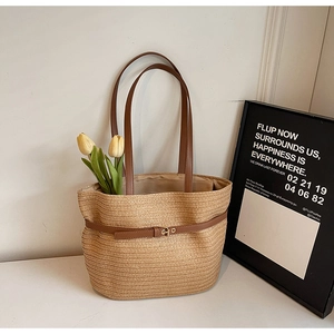 Détail du sac cabas en paille tressée avec anses en cuir marron et boucle en métal doré