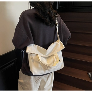 Detailed view of a white canvas crossbody bag with adjustable strap on wooden steps