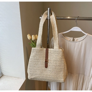 Macro shot of hand-woven straw tote with brown leather strap and metallic buckle