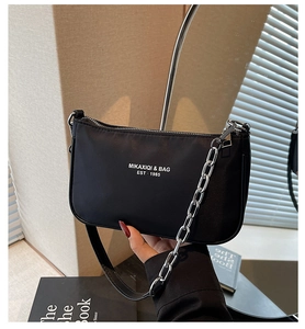 Detail of black crossbody bag with silver chain strap and white printed lettering