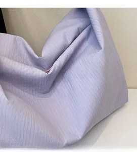 Detail of light purple shoulder bag showing textured vertical pleated fabric and zipper