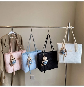 Détails de quatre sacs cabas texturés en plusieurs couleurs avec breloques d'ours