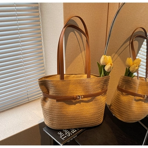 Détail du sac cabas en paille tressée avec lanières en cuir marron et boucle en métal