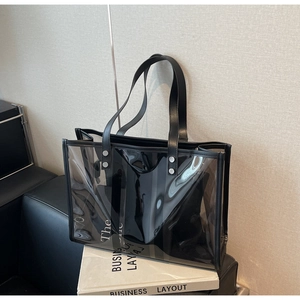 Detail of clear PVC tote bag with black faux leather handles and inner pouch accessory