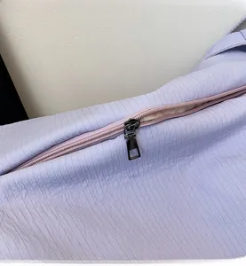 Detailed macro view of the smooth metal zipper on a purple striped fabric tote bag