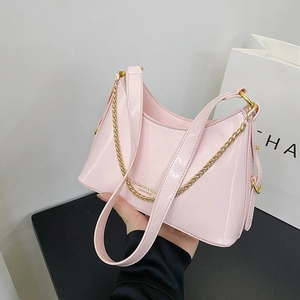 Detailed shot of pink patent leather hobo bag with gold chain and printed fashion text