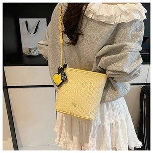 Détail du sac seau jaune tissé avec pendentif en cœur et logo Pan For gravé