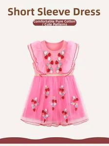 Détails de broderie fraise et couches de tulle sur une robe en coton rose pour fille