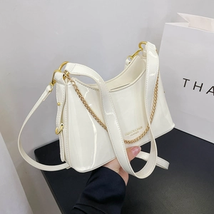 Detail view of white patent leather bucket bag with gold chain and logo decoration
