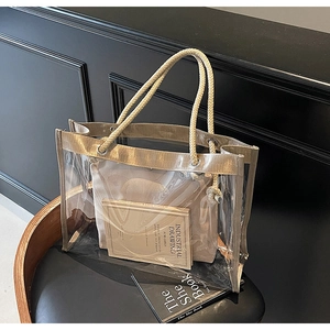 Detailed shot of transparent PVC tote bag with gold woven trim and rustic hemp rope handles