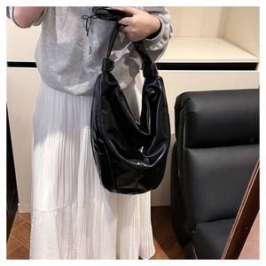 Détail du sac hobo en cuir noir brillant avec un design de sangle nouée élégant