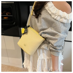 Sac seau jaune avec texture tressée, breloque cœur et logo de marque PAN YORI gravé