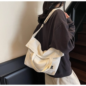 Detailed view of cream canvas tote bag showing side drape and cartoon character patch
