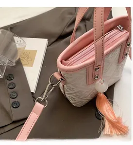 Detail of pink embroidered bucket bag featuring silver hardware and a beaded tassel charm