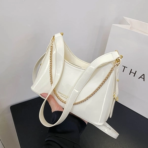Detail of white patent leather bucket bag with gold chain strap and fashion typography