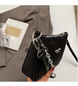 Detail of black satin shoulder bag with silver chunky chain and white printed logo text