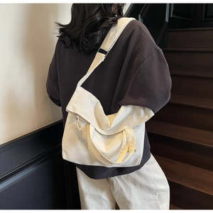 Detail of white canvas crossbody bag showing adjustable strap and large capacity on model