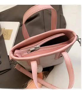 Detail of smooth metal zipper and tassel charm on pink geometric print bucket bag