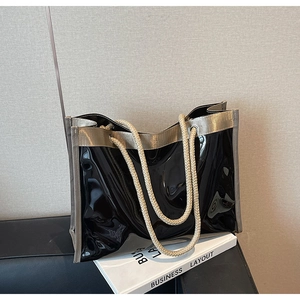 Detail of glossy black tote bag with beige braided rope handles and golden trim edge
