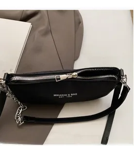 Detailed top view of a black nylon underarm bag with silver chain on books
