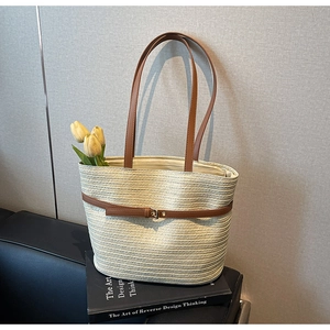 Détail du tissage du sac cabas en paille avec lanière en cuir posé sur un livre d'art
