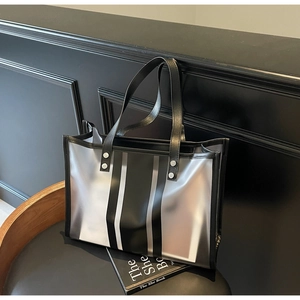 Détail d'un grand cabas transparent en PVC avec rayures noires et rivets argentés