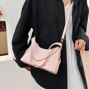 Close-up of pink patent leather crossbody bag with gold chain and metal hardware