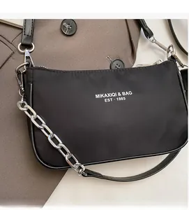 Detail of black nylon shoulder bag with silver chain and white brand typography