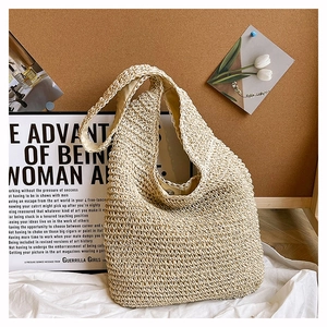 Detailed close-up of a cream woven straw tote bag featuring a magnetic snap closure design