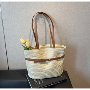 Détail du sac cabas en paille tressée avec poignées en cuir marron et boucle décorative
