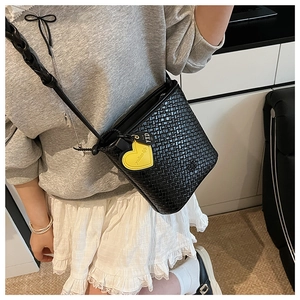 Détail du sac seau tissé avec pendentif cœur jaune vif et texture de matière