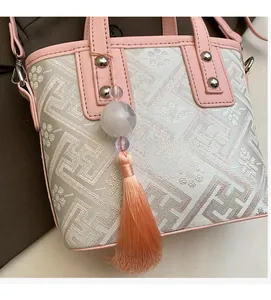Close-up of pink leather edge, geometric pattern fabric and beaded silk tassel detail
